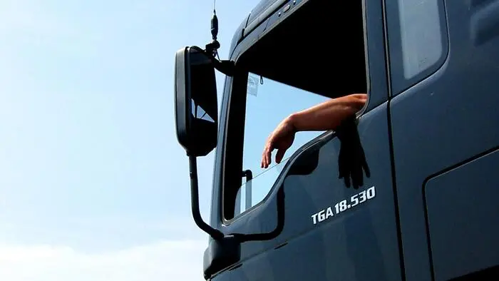 Ein LKW-Fahrer lässt die Hand aus dem Fenster seines Fahrzeuges hängen