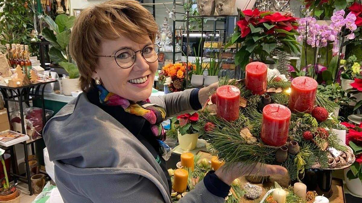 Birgit Brommer mit einem Adventkranz in Rot- und Goldtönen.