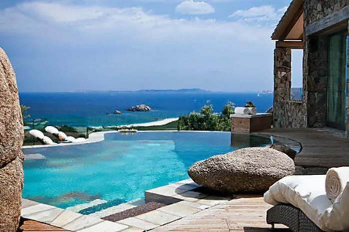 Sardinien. Sonnengeküsste Haut, Salz im Haar und Sand zwischen den Füßen: So blicken Gäste in der Beach Bar Li Caracoli im Resort Valle Dell’Erica der Delphina Hotels &amp; Resorts tiefenentspannt auf das Archipel von La Maddalena mit einem echt-sardischen Cocktail in der Hand. Urlauber kommen direkt vom Strand und sitzen in informeller Atmosphäre zwischen Felsformationen vor einer karibisch anmutenden Meereskulisse. Ein Drink, der gleich zwei traditionell sardische Getränke miteinander verbindet und auch von einem echten Sarden kreiert wurde, ist der Cocktail „Sardo“. Dessen Namensgeber und Erfinder Paolo Sardo mischt für seine Kreation das inseltypische Bier Ichnusa mit dem für Sardinien bekannten „Mirto Rosso“, einem Myritenlikör, und verfeinert das Ganze mit Zitronensaft. Der Likör gibt dem Getränk seine signifikante rote Farbe und sein besonderes Aroma. Paolo steht schon seit fast drei Jahrzehnten hinter der Theke der Bar Li Caracoli ‒ für ihn ist es der schönste Platz auf Erden.