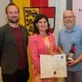 Drei Männer und eine Frau lachen mit der Urkunde in die Kamera