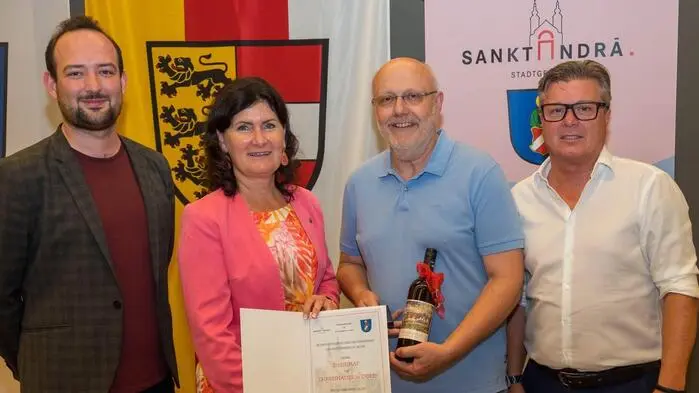 Drei Männer und eine Frau lachen mit der Urkunde in die Kamera
