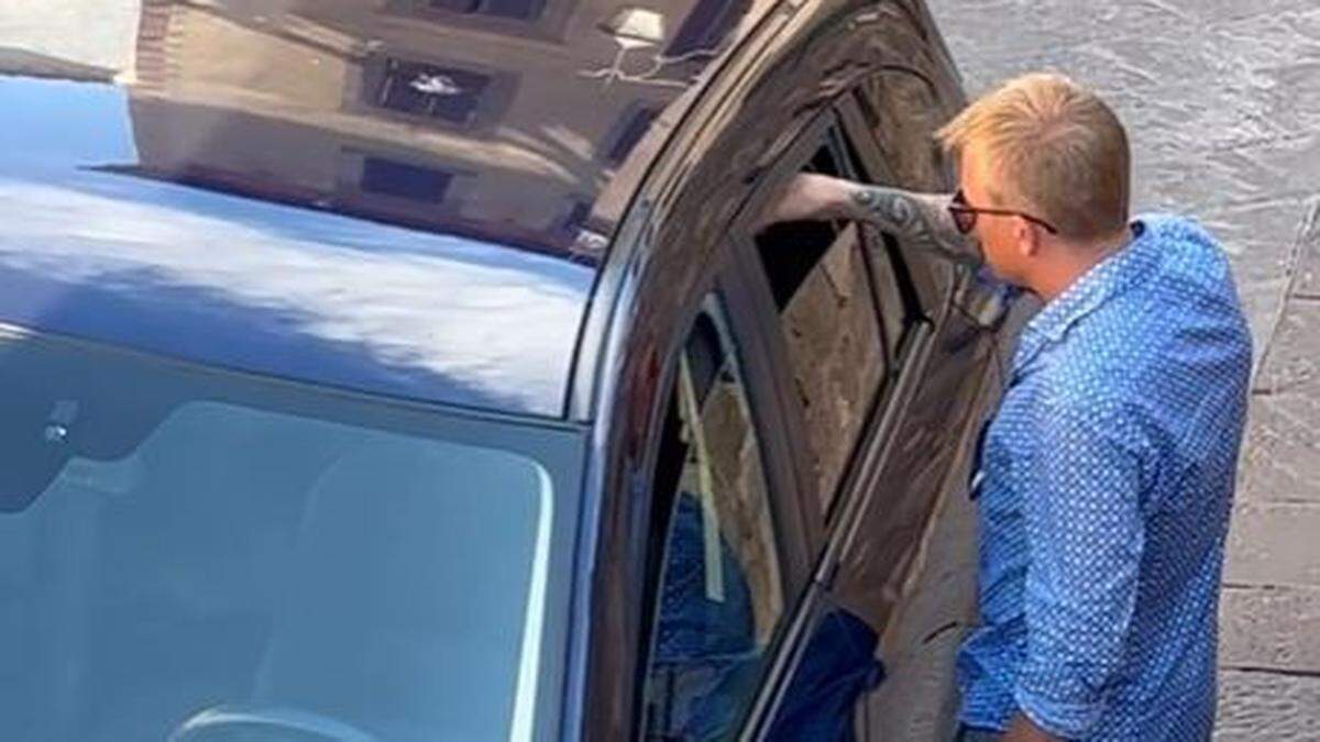 Kimi Räikkönen gibt einem Hund in einem Auto zu trinken.