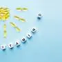 Yellow capsules in the form of the sun with rays and the word vitamin D from white cubes with letters on a blue background. VITAMIN D word for healthy and medical concept. Sunshine vitamin health benefits