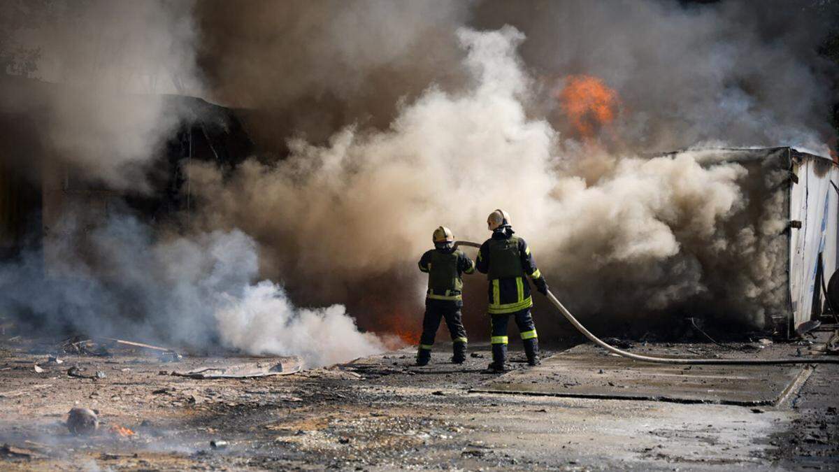 Nach den massiven russischen Luftangriffen am Montag versuchen Feuerwehrleute einen Brand zu löschen