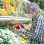 Senior man wearing ffp2 mask to avoid contagion by covid 19 coronavirus shopping in supermarket selecting some fresh product in vegetables department