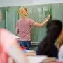 ARCHIV - ILLUSTRATION - Eine junge Lehrerin schreibt am 17.08.2016 in einer Schule in Hannover (Niedersachsen) an eine Schultafel. In Sachsen fehlen Lehrer. Nun behilft man sich im Freistaat mit Seiteneinsteigern. Doch diese Regelung hat nach Ansicht der Gewerkschaft GEW so ihre Tcken. (zu dpa "Sachsens GEW-Landeschefin: Seiteneinsteiger-Regelung belastet Schulen" vom 21.10.2017) Foto: Julian Stratenschulte/dpa +++(c) dpa - Bildfunk+++