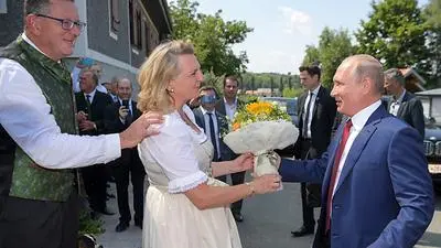 Russian President Vladimir Putin (R) gives a flowers' bouquet to Austrian Foreign Minister Karin Kneissl (C) during her wedding with entrepreneur Wolfgang Meilinger (L) on August 18, 2018 in Gamlitz, Styria, Austria. . / AFP PHOTO / Sputnik / Alexei Druzhinin