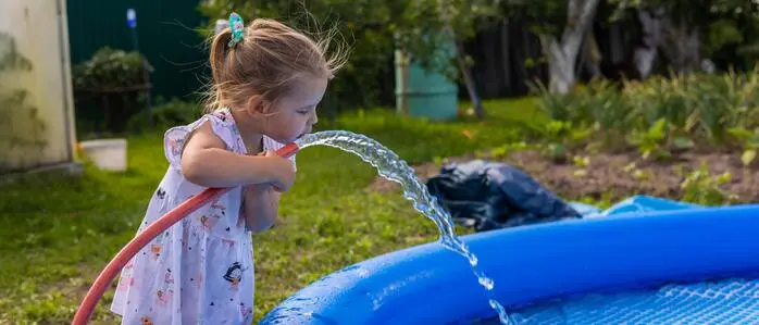 Zu sehen ist ein Mädchen, das aus einem Wasserschlauch trinkt 