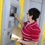 Eine Frau mit einem Paket bei einem Postabgabeautomaten | Auch wie mit Retouren umgegangen wird, ist noch offen