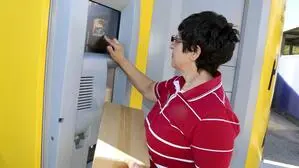 Eine Frau mit einem Paket bei einem Postabgabeautomaten | Auch wie mit Retouren umgegangen wird, ist noch offen