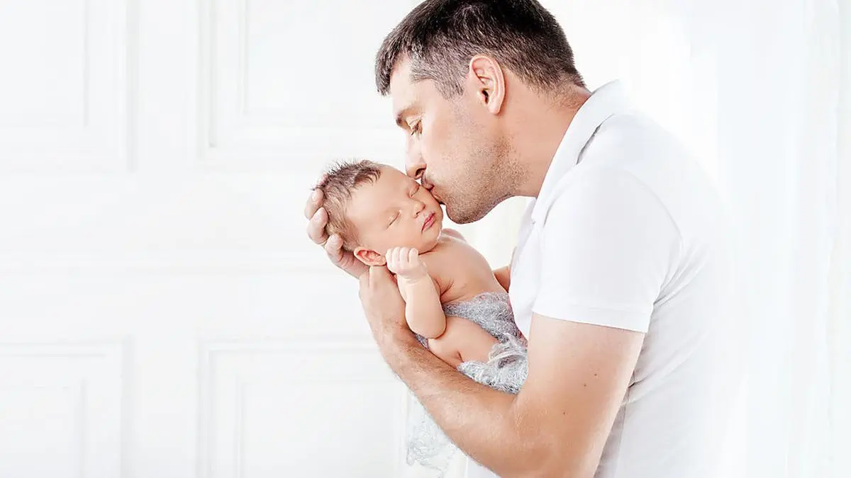 Father holding his newborn baby in  hands. Father kissing his baby