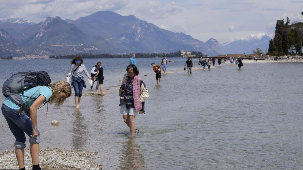 Touristen wateten zu Fuß zur Insel San Biagio im Gardasee