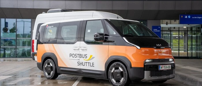 Ein organge-schwarz-weißer Bus steht vor einem Bahnhof