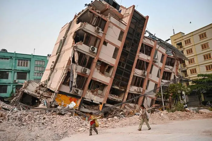 TOPSHOT - Children walk past a collapsed building in Mandalay on April 2, 2025, five days after a major earthquake struck central Myanmar. Days after a shallow 7.7-magnitude earthquake that killed more than 2,000 people, many people in Myanmar are still sleeping outdoors, either unable to return to ruined homes or afraid of further aftershocks. (Photo by AFP)