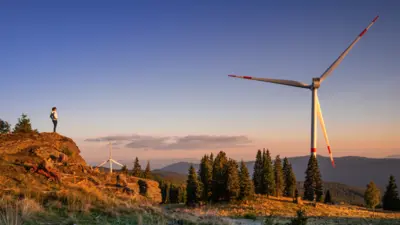 Windräder und eine Wanderin auf einem Berg