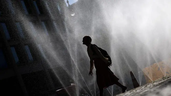 Man sieht eine Person durch Sprinkleranlagen gehen