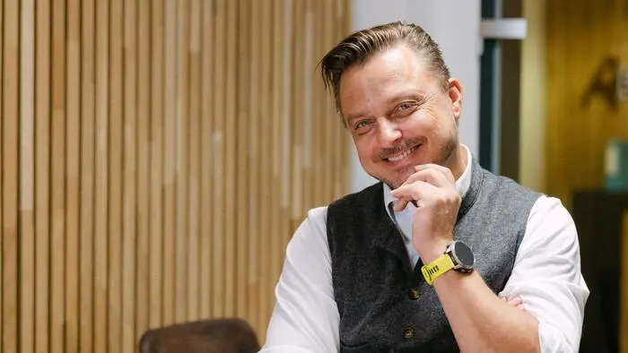Ein Mann sitzt an einem Tisch und lächelt.