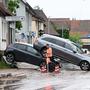 Auf einer Straße in Miedelsbach stehen Fahrzeuge, die durch ein Hochwasser nach einem Unwetter weggespült wurden. Seit Tagen kämpfen die Helfer in Bayern und Baden-Württemberg gegen die Flut und ihre Folgen