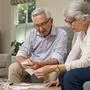 Smiling senior couple with papers, calculators and bills at home. Senior couple calculating taxes at home. Mature man and woman wearing spectacles and looking their expenses together.