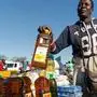 A customer buys cooking oil at a stall where smaller than standard measures of cooking oil is sold at Harare Mbare Musika marketplace on July 15, 2019. - Zimbabwe's annual inflation rate hit 175 percent in June, official data showed on July 15, 2019, stoking fears of a return of the hyperinflation that wiped out savings ten years ago when the economy collapsed. Supplies of essentials such as bread, medicine and petrol have regularly run short in the country as price increases hit their fastest pace since the government was forced to abandon the Zimbabwe dollar in 2009. (Photo by Jekesai NJIKIZANA / AFP)