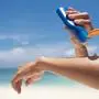 Woman applying sunscreen on her hands from a bottle on the beach with the sea in the background. SPF sunblock protection concept.selective focus