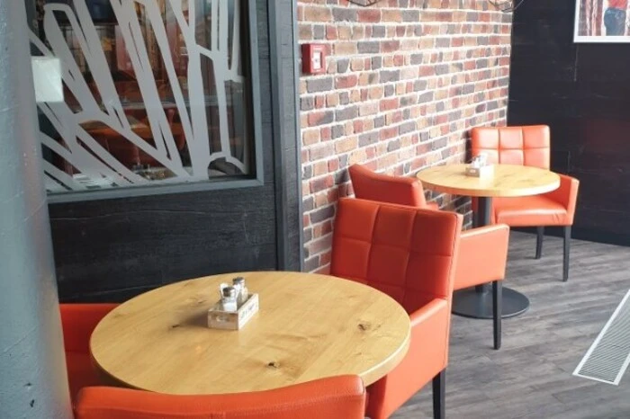 Knallorange Stühle, stylische Lampen, Wände in Ziegel-Optik.