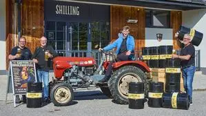 Vier Männer auf einem Oldtimer-Traktor und Bierfässern