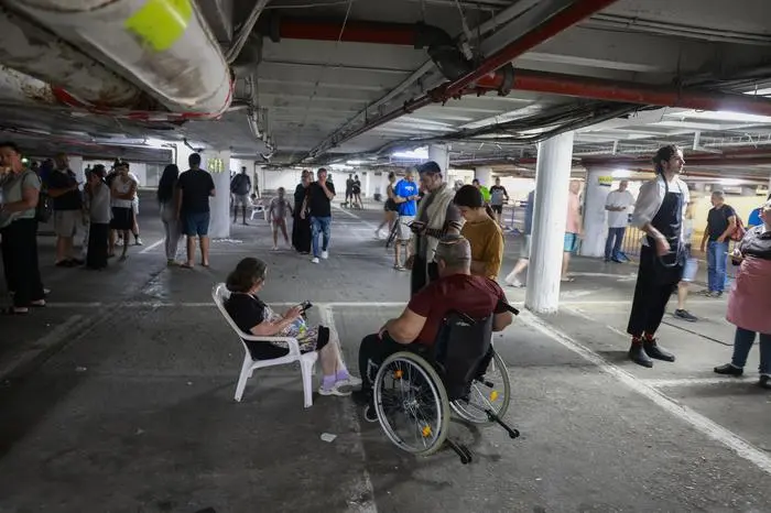 People take shelter in a parking lot in Tel Aviv amid a fresh barrage of Iranian rockets on June 17, 2025. Israel's military said air raid sirens sounded in several areas of the country on June 17 after identifying missiles launched from Iran, as AFP journalists reported booms over Tel Aviv and Jerusalem. (Photo by Menahem KAHANA / AFP)