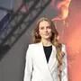 Lisa-Marie Schiffner in einem weißen Hosenanzug vor einem Plakat, auf dem der Teil eines Krans und eine Flamme zu sehen ist.
