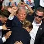 TOPSHOT - Republican candidate Donald Trump is seen with blood on his face surrounded by secret service agents as he is taken off the stage at a campaign event at Butler Farm Show Inc. in Butler, Pennsylvania, July 13, 2024. Donald Trump was hit in the ear in an apparent assassination attempt by a gunman at a campaign rally on Saturday, in a chaotic and shocking incident that will fuel fears of instability ahead of the 2024 US presidential election.
The 78-year-old former president was rushed off stage with blood smeared across his face after the shooting in Butler, Pennsylvania, while the gunman and a bystander were killed and two spectators critically injured. (Photo by Rebecca DROKE / AFP)