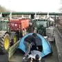A farmer sets up his tent on the trailer of his tractor on a highway, Monday, Jan. 29, 2024 in Argenteuil, north of Paris. Protesting farmers were encircling Paris with tractor barricades and drive-slows on Monday, using their lumbering vehicles to block highways leading to France's capital to pressure the government over the future of their industry, which has been shaken by repercussions of the Ukraine war. (AP Photo/Christophe Ena)