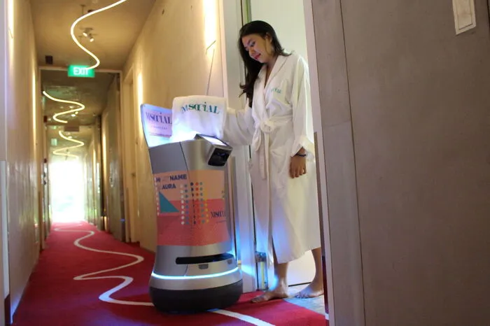 Im M Social Hotel Singapur unterstützt der Roboter “Aura” das Room-Service Team und liefert die Bestellung direkt ins Zimmer. Mitarbeiter können den Roboter mit den gewünschten Bestellungen bestücken und eingeben, wohin geliefert werden soll. Der Roboter kann sogar selbstständig die Aufzüge bedienen und lässt die Gäste per Anruf wissen, wann ihre Bestellung bereitgestellt wird. Die Klappe öffnet automatisch, sobald die Gäste die Tür aufmachen. Anschließend begibt sich Aura wieder zu ihrer Dockingstation zurück.