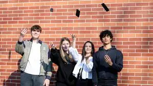 Das Bild zeigt vier Schülerinnen und Schüler, die ihre Handys in die Luft werfen