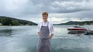 Ein junger Erwachsener steht in Kochkleidung vor einem See