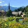 Ein bunt blühender Kräutergarten, im Hintergrund eine Kirchturmspitze