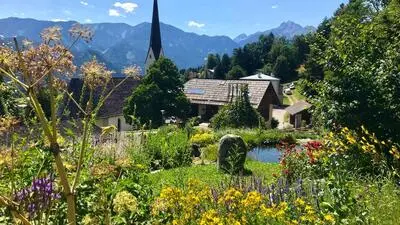Ein bunt blühender Kräutergarten, im Hintergrund eine Kirchturmspitze