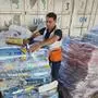 FILE - A United Nations worker prepares aid for distribution to Palestinians at UNRWA warehouse in Deir Al-Balah, Gaza Strip, on Monday, Oct. 23, 2023. The spokesperson for Israel's welfare ministry says it has stopped providing the documentation needed for international aid workers to renew their visas because the ministry does not have the investigative muscle to look into their potential militant affiliations.  (AP Photo/Hassan Eslaiah, File)