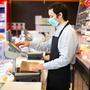 Shopkeeper running business while wearing mask, coronavirus pandemic concept
