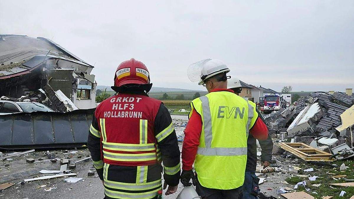 Einsatzkräfte vor dem völlig zerstörten Haus