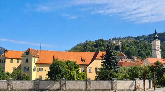 Ein gelbes Schloss umgeben von einer hohen Mauer, daneben sieht man den Turm der Markuskirche