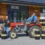 Vier Männer auf einem Oldtimer-Traktor und Bierfässern