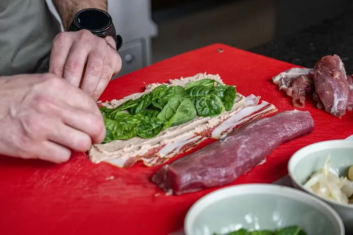 300 g Wollschweinbauchspeck werden überlappend ausgelegt. Die Wollschwein-Farce darauf gleichmäßig verteilen und mit dem gewaschenen Spinat belegen.