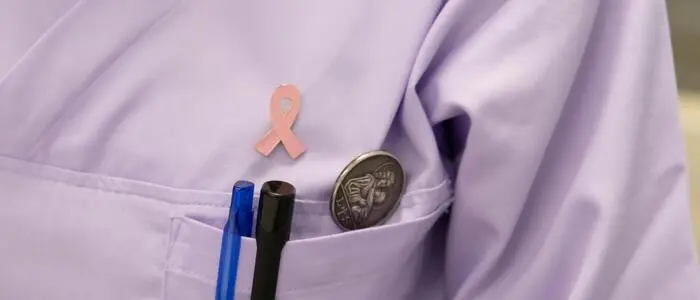 Man sieht eine Ärztin mit pinker Schleife an der Brust