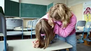 Das Foto zeigt eine Schülerin, die eine weitere im Schwitzkasten hält und auf einen Tisch drückt