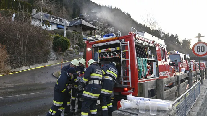 Eine lange Reihe von Einsatzfahrzeugen an der Bundesstraße vor der Brandruine.