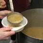 Aus einem großen Topf wird Suppe geschöpft