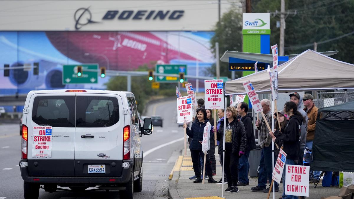 Boeing workers greet other union members in a support van as they strike after voting to reject a contract offer Sunday, Sept. 15, 2024, near the company's factory in Everett, Wash. (AP Photo/Lindsey Wasson)