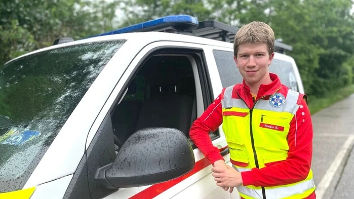 Ein junger Wasserretter steht neben seinem Einsatzfahrzeug