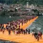 Visitors walk across floating piers covered in orange fabric as part of the project 'The Floating Piers' by Christo on Lago d'Iseo lake off of Paratico, Italy, 18 June 2016. Christo had a pier built from Paratico to the island of Pesciera and covered the pier and shore in fabric. The art project by Christo on the northern Italian lake opens on 18 June and continues until 03 July 2016. Photo: MICHAEL KAPPELER/dpa