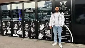 Ein dunkelhaariger Mann in Jeans und Winterjacke steht vor einem Geschäft und lächelt | Yehia Bazara hat den Barbershop „Ti Amo“ eröffnet